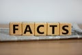 Cubes placed on a newspaper form the word `facts`. Beautiful wooden table. White background. Business concept. Copy space Royalty Free Stock Photo