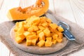 Cubes of pumpkin on cutting board and knife on wooden table Royalty Free Stock Photo