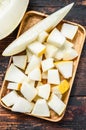 Cubes of sliced yellow melon on a wooden tray. Dark wooden background. Top view Royalty Free Stock Photo