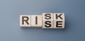 cubes turning message RISK to RISE. Turned wooden cubes with words Risk vs Rise. Blue background. Business and Rise vs Risk