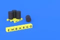 Cubes with word embargo near black barrels on pallet