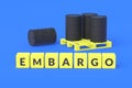 Cubes with word embargo near black barrels on pallet