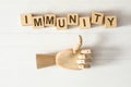 Cubes with word Immunity and mannequin hand showing thumb up gesture on white wooden table, flat lay