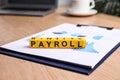 Cubes with word Payroll and chart on wooden table