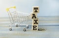 Cubes with word Taxe and stacked coins on wooden surface. Royalty Free Stock Photo