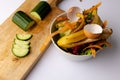 Cucumber on chopping board with organic food waste in kitchen composting bin Royalty Free Stock Photo