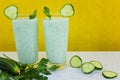 Cucumber cocktail, fresh vegetable smoothie, parsley leaves and cucumber on a yellow background