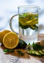 Cucumber mint ginger and lemon detox water with ingredients on wooden table.