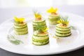 cucumber rounds layered with dill on white plate