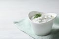 Cucumber sauce in ceramic bowl on wooden background, space for text