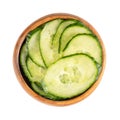 Fresh salad cucumber with skin, diagonally sliced, in a wooden bowl