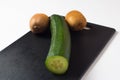 A cucumber and two kiwis lie on a black cutting Board. Diet food and salads for a healthy lifestyle. The likeness of a phallic