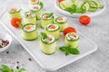 Cucumbers rolls with cream cheese, salted salmon and fresh herbs served on a white ceramic board on a concrete background. Royalty Free Stock Photo