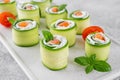 Cucumbers rolls with cream cheese, salted salmon and fresh herbs served on a white ceramic board on a concrete background. Royalty Free Stock Photo