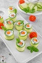 Cucumbers rolls with cream cheese, salted salmon and fresh herbs served on a white ceramic board on a concrete background. Royalty Free Stock Photo