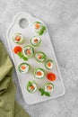 Cucumbers rolls with cream cheese, salted salmon and fresh herbs served on a white ceramic board on a concrete background. Royalty Free Stock Photo