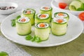 Cucumbers rolls with cream cheese, salted salmon and fresh herbs served on a white plate on a concrete background. Selective focus Royalty Free Stock Photo