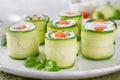 Cucumbers rolls with cream cheese, salted salmon and fresh herbs served on a white plate on a concrete background. Selective focus Royalty Free Stock Photo