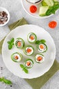 Cucumbers rolls with cream cheese, salted salmon and fresh herbs served on a white plate on a concrete background. Selective focus Royalty Free Stock Photo