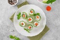 Cucumbers rolls with cream cheese, salted salmon and fresh herbs served on a white plate on a concrete background. Selective focus Royalty Free Stock Photo