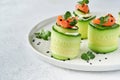 Cucumbers rolls with soft cheese, pieces of salted salmon, microgreens and black sesame served on a white plate. Holiday vegetable Royalty Free Stock Photo