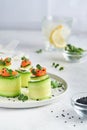 Cucumbers rolls with soft cheese, pieces of salted salmon, microgreens and black sesame served on a white plate. Holiday vegetable Royalty Free Stock Photo