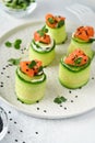 Cucumbers rolls with soft cheese, pieces of salted salmon, microgreens and black sesame served on a white plate. Holiday vegetable Royalty Free Stock Photo
