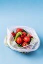 Cucumbers and tomatoes in plastic bag on blue background. Stop using artificial food storage bags concept