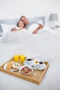 Cuddling couple sleeping with breakfast tray on bed Royalty Free Stock Photo