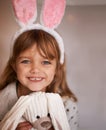 Cuddly companion. Portrait of an adorable little girl wearing bunny ears and holding her toy rabbit. Royalty Free Stock Photo