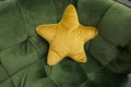 A cuddly yellow star-shaped pillow on a green sofa Royalty Free Stock Photo