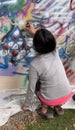 Cuenca, Ecuador, Dec 9, 2021 - Child sprays wall to learn street art (grafitti)