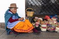 An elderly ecuadorian woman weaves a straw basket