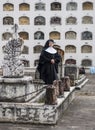 Cuenca, Ecuador - November 1, 2015 -a Catholic nun stands in front of wall of graves in a cemetary condominium