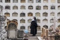 Cuenca, Ecuador - November 1, 2015 -a Catholic nun stands in front of wall of graves in a cemetary condominium