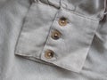 Cuffs. Beige three-button cuff on a grey organic linen shirt. Details of natural clothing. Comfortable style cloth.