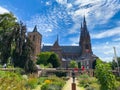 View over garden on monumental gothic church against blue sky in summer
