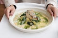 Cuisine of Halibut fish in a white plate with hands in frame