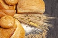 Culinary background with bread,sweet bun,wheat ears,grains on a black background, top view Royalty Free Stock Photo