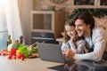 Culinary Blog. Cheerful Young Dad And Little Girl Using Laptop In Kitchen