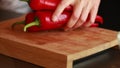 culinary finesse: woman hands cutting fresh red bell peppers on wooden board closeup