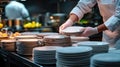 Professional chef stacking clean plates in a busy kitchen setting with stainless steel appliances and utensils in the ba Royalty Free Stock Photo