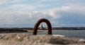 Cullercoats church overlooking Tynemouth Longsands beach, viewed through an old rusty Dock Ring on Tynemouth`s North Pier