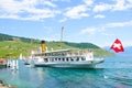 Cully, Switzerland - August 11, 2019: Tourist boat with passengers on Geneva Lake. Vineyards on the slopes in background. Lavaux