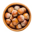 Cultivated hazelnuts in wooden bowl over white