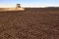 cultivator operates on ploughed field makes dust