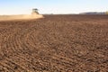 Cultivator operates on ploughed field near spring forest