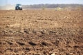 cultivator raises great dust with ploughed soil on foreground