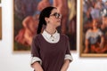 Cultural education. Portrait of caucasian pretty young woman wearing glasses visiting excursion in museum, contemplates Royalty Free Stock Photo