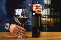 The culture of winemaking. Samelie offers wine, the hands of a winemaker with a glass of wine and an uncorked bottle Royalty Free Stock Photo